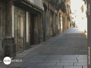 Dieses Bild von unserer Camino Portugues Tour zeigt eine leere gepflasterte Gasse in Vigo, links eine H&auml;userzeile mit braunen Geb&auml;uden.
