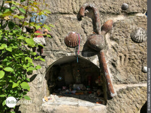 Kleine Jakobswegzeichen auf dem Camino Portugues Rundwanderweg Hier sieht man eine kleine in eine Mauer eingelassene Gedenkstätte geschmückt mit Wanderstab und Jakobsmuscheln in der Nähe der Ortschaft Arcade.