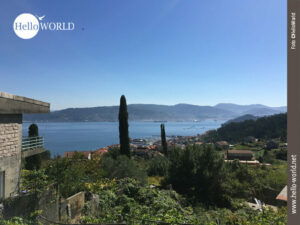 Ein wunderbarer Blick zurück auf Pontevedra Bay Der Camino Portugues bietet vom Berg aus einen tollen Ausblick: vor blauem Himmel liegt „ Ria de Pontevedra Bay“. Im Vordergrund viel grün, dahinter der Ort Cambarro.