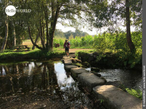 Hier sieht man eine Pilgerin, die den Rego da Armenteira auf Trittsteinen &uuml;berquert.
