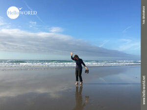 Weiter Strand am Praia das Catedrais Das Bild vom Camino del Norte entstand am Praia das Catedrais und zeigt eine winkende Frau am Strand.