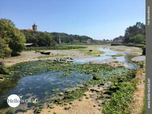 Das Bild von der spanischen Nordk&uuml;ste zeigt ein ausgetrocknetes Flussbett mit Blick nach Barro und den Turm der Parroquia de Nuestra Se&ntilde;ora de los Dolores de Barro.