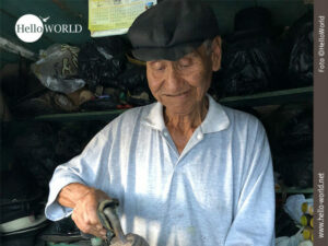 Das Bild aus Bolivien zeigt einen alten Hutmacher beim B&uuml;geln eines Hutes in seiner winzigen Werkstatt.