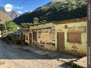 Auf dieser Aufnahme aus der Serie Bilder aus S&uuml;damerika, sind zerfallene Buden an einem Stra&szlig;enrand eines Dorfes zu sehen, im Hintergrund Berge.
