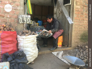 Hier sieht man ein Foto aus der Serie Bilder aus S&uuml;damerika, das aus einem kleinen Dorf stammt und einen Kartoffelh&auml;ndler beim Zeitunglesen zeigt.