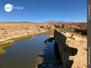 Dieses Bild zeigt die bolivianische Laguna Negra, auf deren Seiten r&ouml;tliche Felsw&auml;nde emporragen.