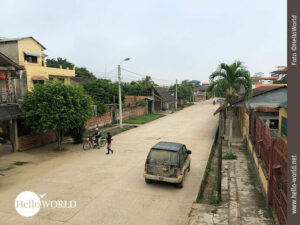 Das Bild aus Rurrenabaque, Bolivien, zeigt eine befestigte Stra&szlig;e, rechts und links H&auml;user, vorne ein parkendes Auto.