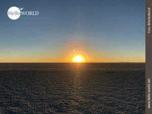 Die Sonne geht auf in der Salar de Uyuni Dieses Bild aus der Salar de Uyuni in Bolivien zeigt die glutrote Sonne, die am Horizont erscheint.