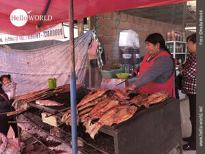 Frisch vom Grill: Streetfood auf dem Mercado el Morro Das Bild vom Mercado el Morro in Sucre, Südamerika, zeigt eine Frau, die an einem Grill Fisch zubereitet.