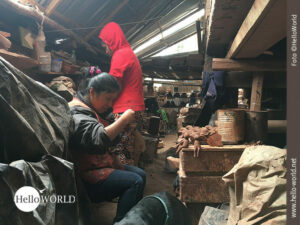 Das Bild aus einer T&ouml;pferei in Ecuador zeigt zwei Frauen, die vordere sitzt vor kleinen Tonfiguren, die hintere mit roter Kapuzenjacke steht.