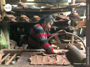 Das Bild aus Ecuador zeigt eine Frau in einer T&ouml;pferei die auf einer Fl&auml;che gleichm&auml;&szlig;ig Ton ausbreitet, dahinter ein Regal mit T&ouml;pferwaren.