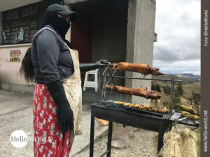 Das Bild aus Ecuador zeigt eine Frau vor einem Grill auf dem Cuys aufgespie&szlig;t sind.