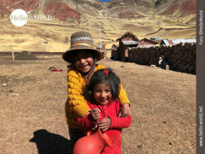 Das Bild aus S&uuml;damerika zeigt zwei lachende Kinder auf einem Feld, im Hintergrund Berge.