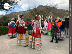 Dieses Bild aus Chivay, Peru, zeigt zwei M&auml;dchen in bunten Trachten, dahinter eine Menschenansammlung in Trachten.