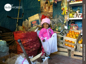 Dieses Bild zeigt den Innenraum eines kleinen Dorfladens im Colca Canyon, Peru, in dem ein kleines pink-farben bekleidetes M&auml;dchen mit einer Einkaufst&uuml;te zwischen Obst und Gem&uuml;se steht.