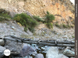 Dieses Bild zeigt eine Nahaufnahme einer einfachen Holzbr&uuml;cke ohne Gel&auml;nder, die &uuml;ber den mit wenig Wasser gef&uuml;llten Rio Colca f&uuml;hrt.