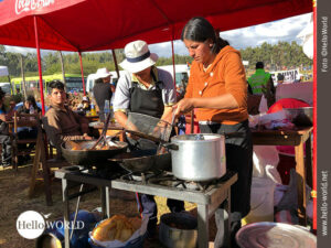 Gemeinsam am "Freiluft-Herd" Das Bild aus Cusco, Peru, zeigt zwei Frauen an einer Kochstelle auf dem Sonnenfest, über ihnen ein roter Schirm.
