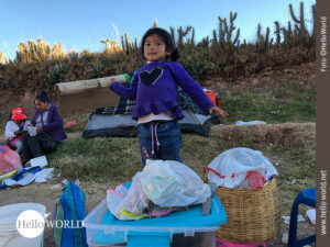Jetzt wird der Tisch gedeckt ... Dieses Bild vom Sonnenfest in Cusco, Peru, zeigt ein kleines Mädchen das auf einem Grashügel steht und dabei ist ein Matte auszubereiten.