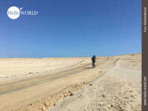 Weit sind die Wege im Nationalreservat Paracas Dieses Bild aus dem Nationalreservat Paracas in Peru zeigt einen Mountainbiker von hinten der eine sandige Piste entlang fährt.
