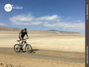 Mit dem Mountainbike im Nationalreservat Paracas Dieses Bild aus dem Nationalreservat Paracas zeigt Nico auf einem Mountainbike eine Sandpiste entlang fahren und in die Kamera lächeln.